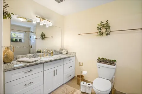 a bathroom with a granite countertop sink a toilet and mirror