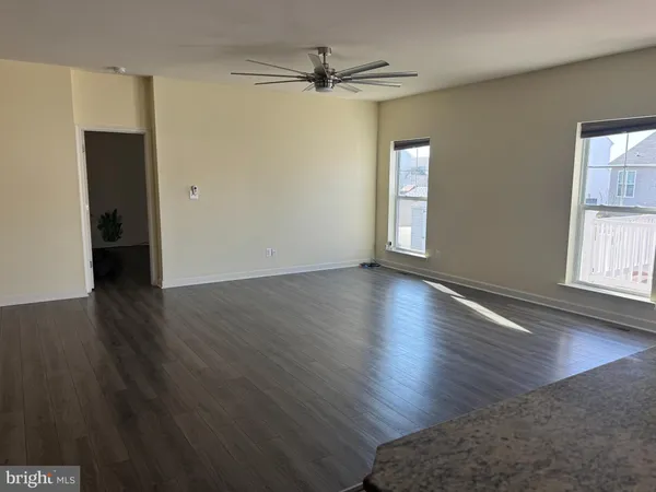 an empty room with wooden floor chandelier fan and windows