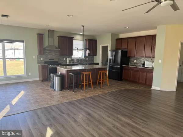 a kitchen with stainless steel appliances granite countertop a refrigerator a sink dishwasher a stove and a dining table with wooden floor