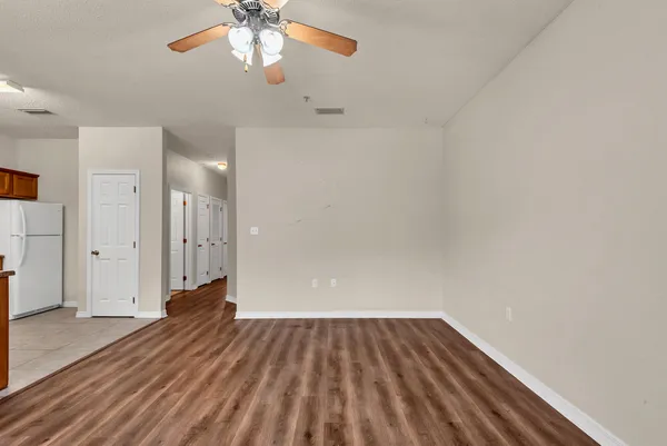 a view of a room with wooden floor a ceiling fan and windows