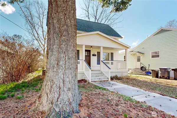 a view of a white house next to a road and yard