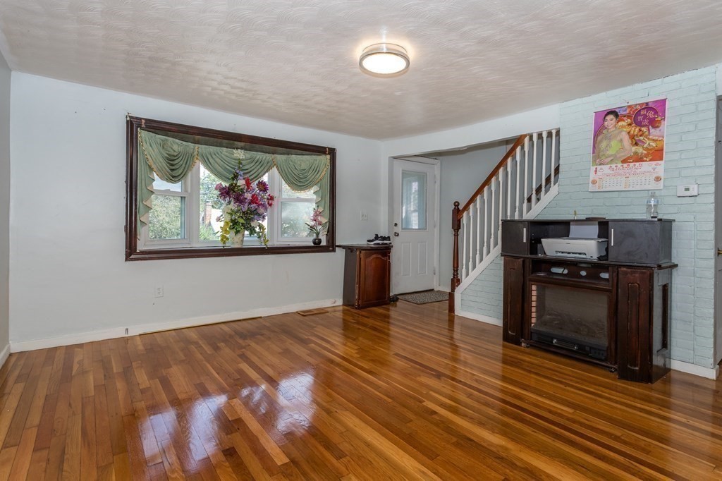 59 Weyham Road Weymouth, MA 02191 - Photo 6 of 18 a view of an empty room with wooden floor fireplace and a window