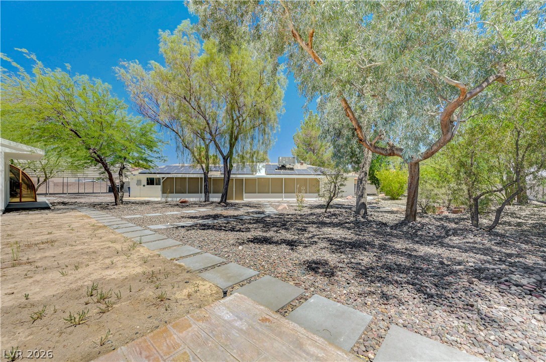 7631 Bermuda Road Las Vegas, NV 89123 - Photo 44 of 64 A spacious backyard with mature trees provides ample shade, with a concrete pathway leading to the home's screened-in patio.