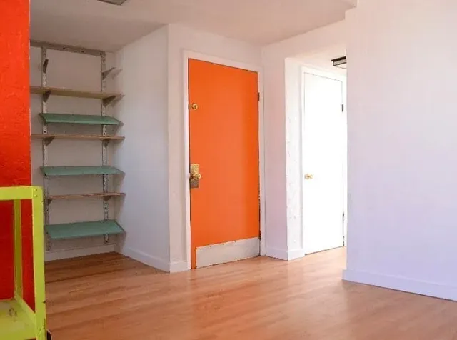 a view of an empty room with wooden floor and closet