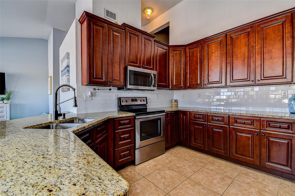 5309 Boardwalk Street Holiday, FL 34690 - Photo 14 of 50 a kitchen with stainless steel appliances granite countertop a sink stove and microwave