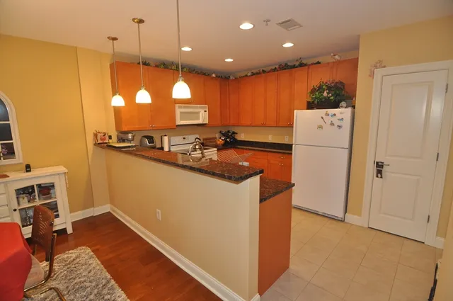 a kitchen with a refrigerator a stove and a dining table with wooden floor