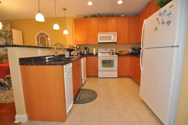 a kitchen with stainless steel appliances granite countertop a refrigerator a stove a sink and a microwave
