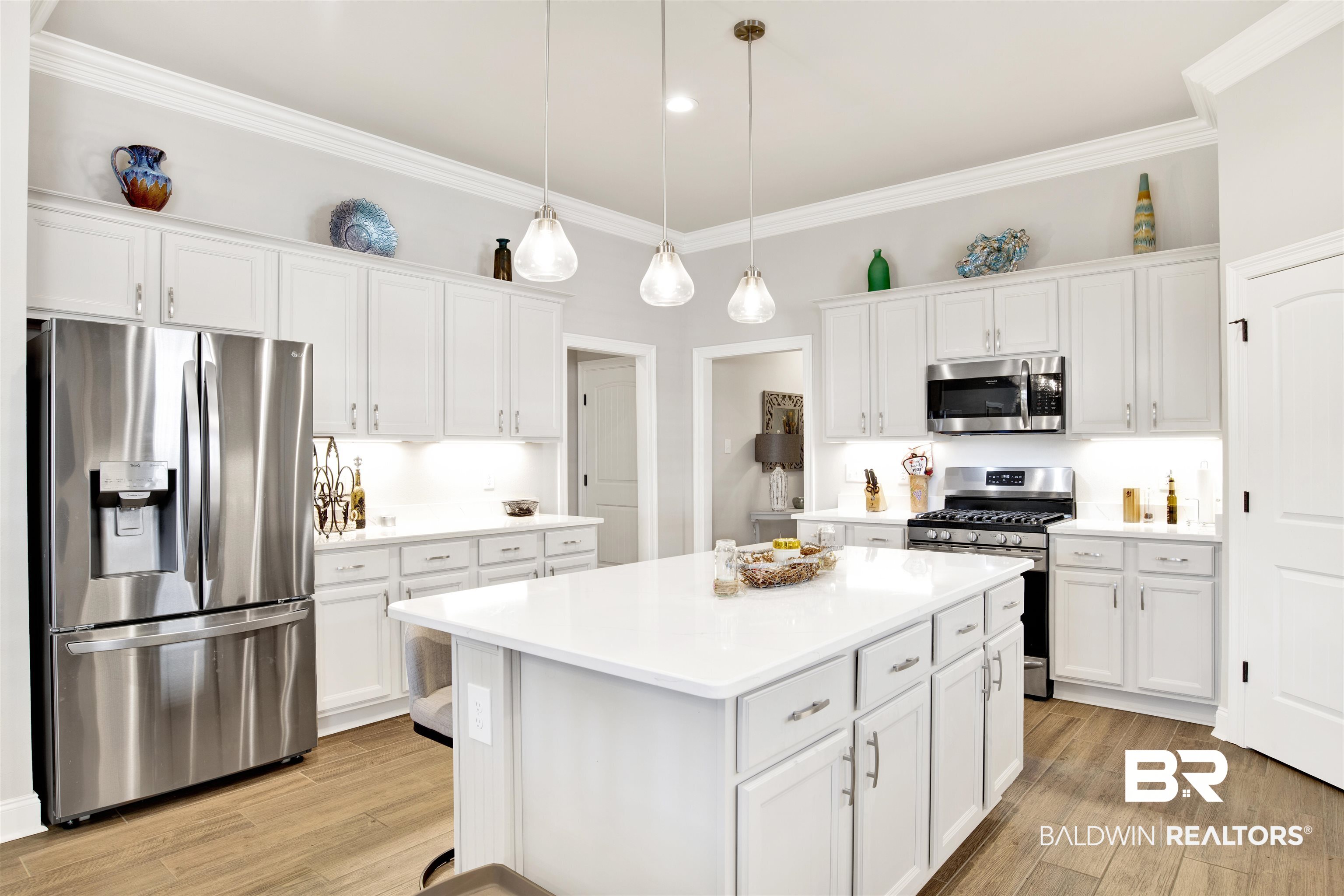 1406 Aldon Street Foley, AL 36535 - Photo 11 of 30 Kitchen with light gray cabinetry, hanging light fixtures, luxury wood-look tile flooring, a kitchen island, and appliances with stainless steel finishes.