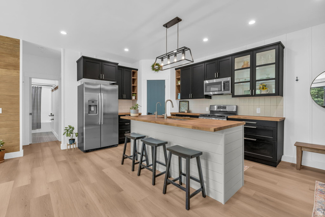 1766 West Tollgate Cyn Road Coalville, UT 84017 - Photo 32 of 59 Kitchen featuring a central island with wood-finish countertop, stainless steel appliances, black cabinetry, white shiplap island paneling, and wood-finish flooring