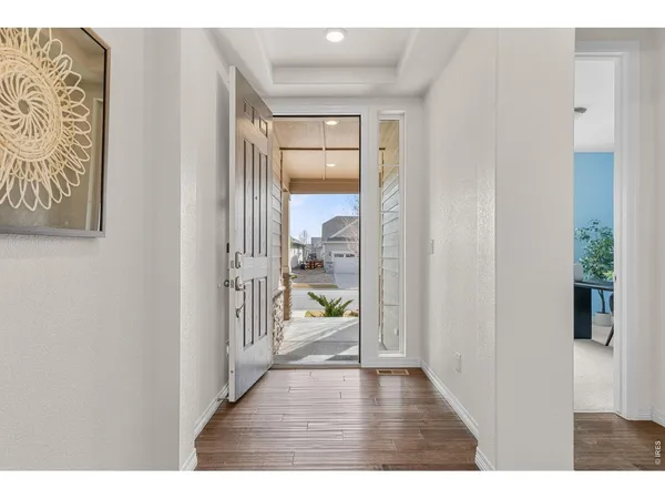 a view of a hallway with wooden floor and a living room
