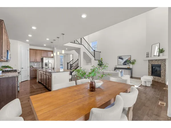 a living room with fireplace furniture dining table and a kitchen view