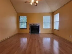 an empty room with windows fireplace and wooden floor