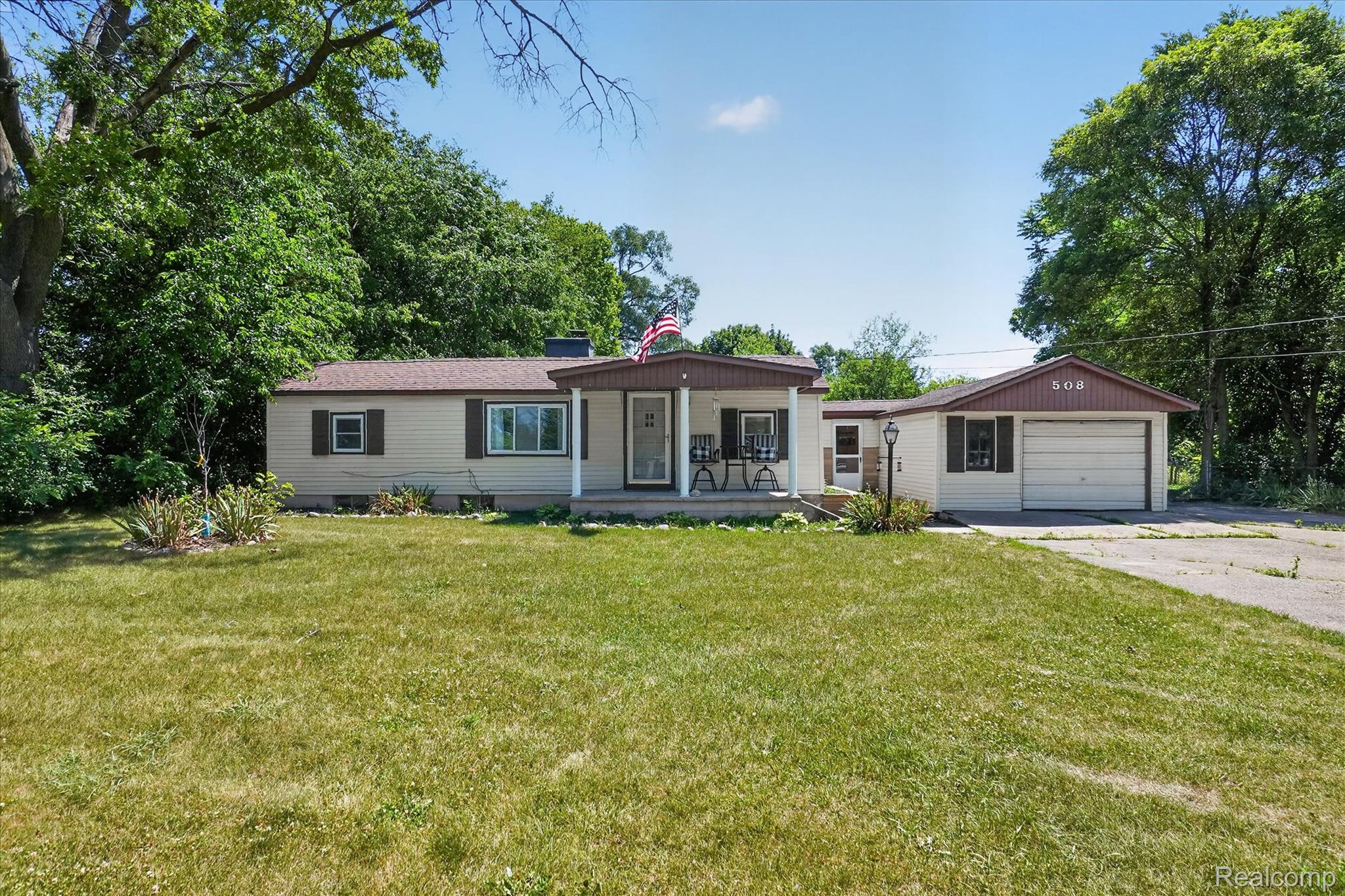 508 Deland Road Flushing, MI 48433 - Photo 2 of 38 Ranch-style residence featuring a covered front porch, an attached single-car garage, and a wide driveway