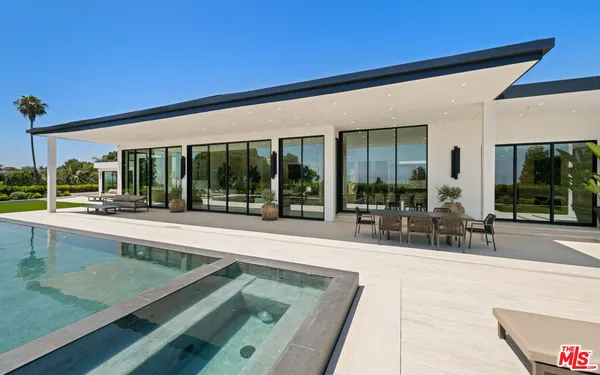 a view of swimming pool with seating area and trees in the background