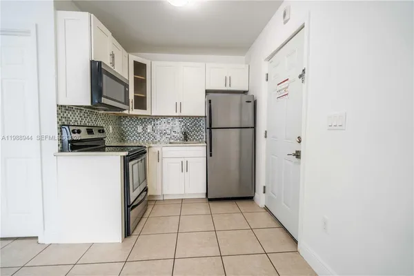a kitchen with a refrigerator sink stove and cabinets
