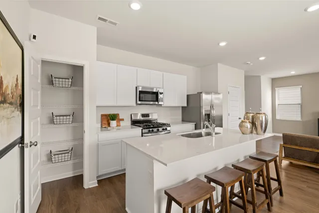 a kitchen with stainless steel appliances a refrigerator a stove a sink a dining table and chairs