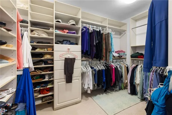a view of walk in closet with clothes and shoes
