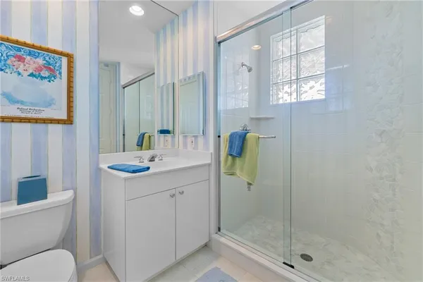 a bathroom with a granite countertop sink a toilet and shower