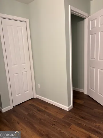 an empty room with wooden floor and closet area