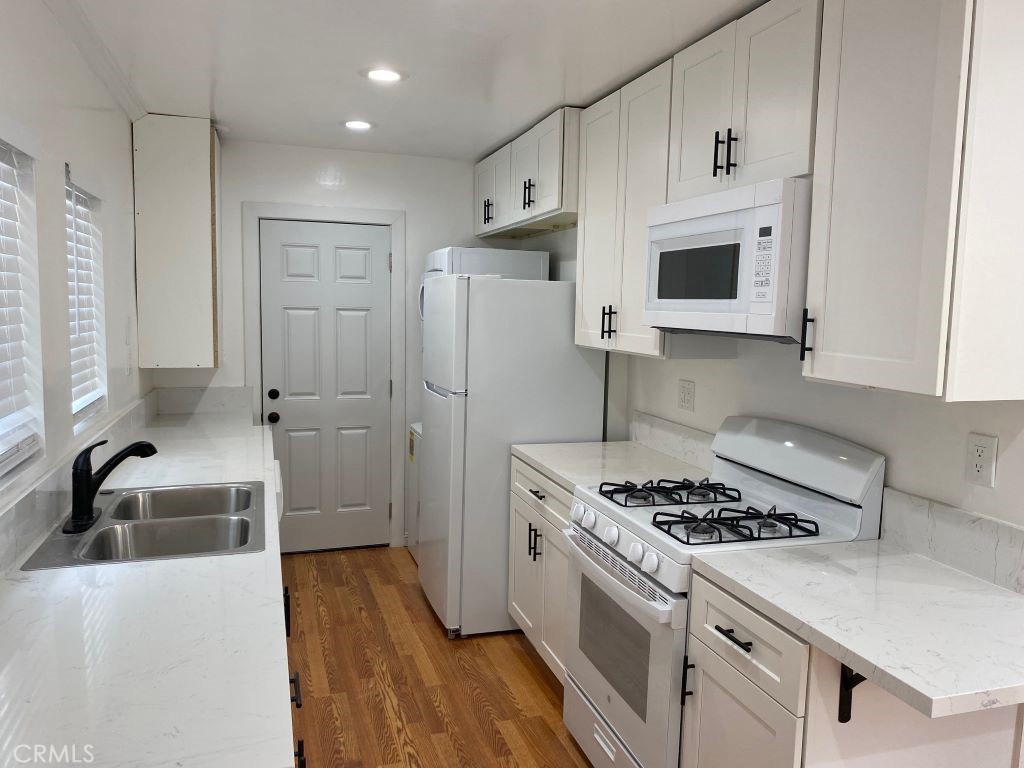 1140 1/2 South Oxford Avenue Los Angeles, CA 90006 - Photo 3 of 14 a kitchen with stainless steel appliances a sink a stove a microwave a refrigerator and cabinets