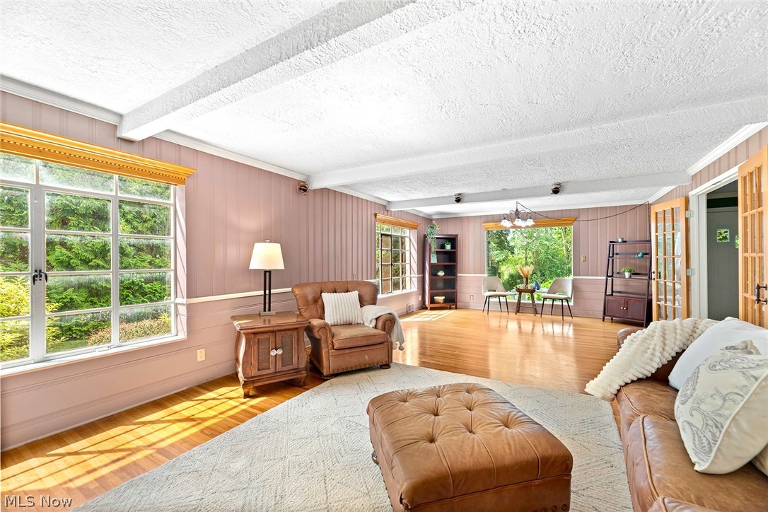 1375 North Revere Road Akron, OH 44333 - Photo 15 of 50 Hardwood flooring, white beamed ceiling, large divided-light windows, paneled walls, and French doors