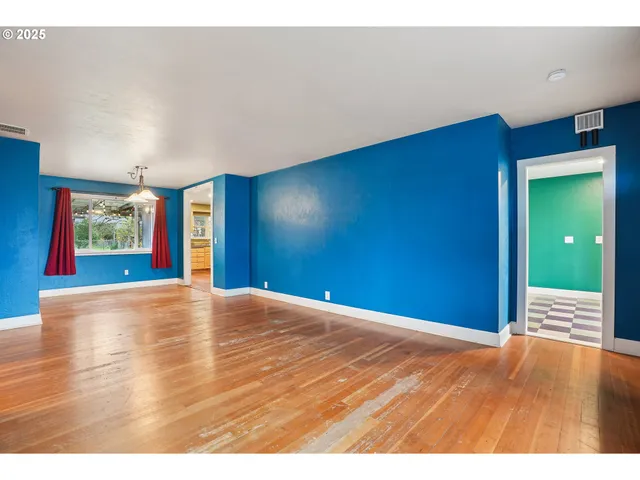 a view of empty room with window and wooden floor