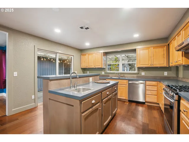 a kitchen with stainless steel appliances granite countertop a sink stove and wooden cabinets