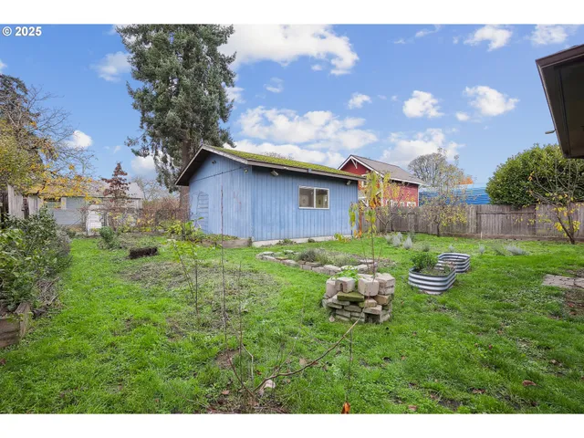 a backyard of a house with table and chairs plants and large tree