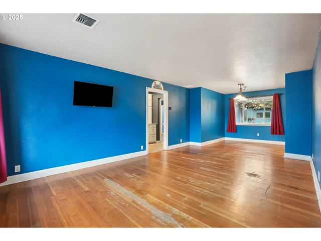 a view of an empty room with wooden floor and a flat screen tv
