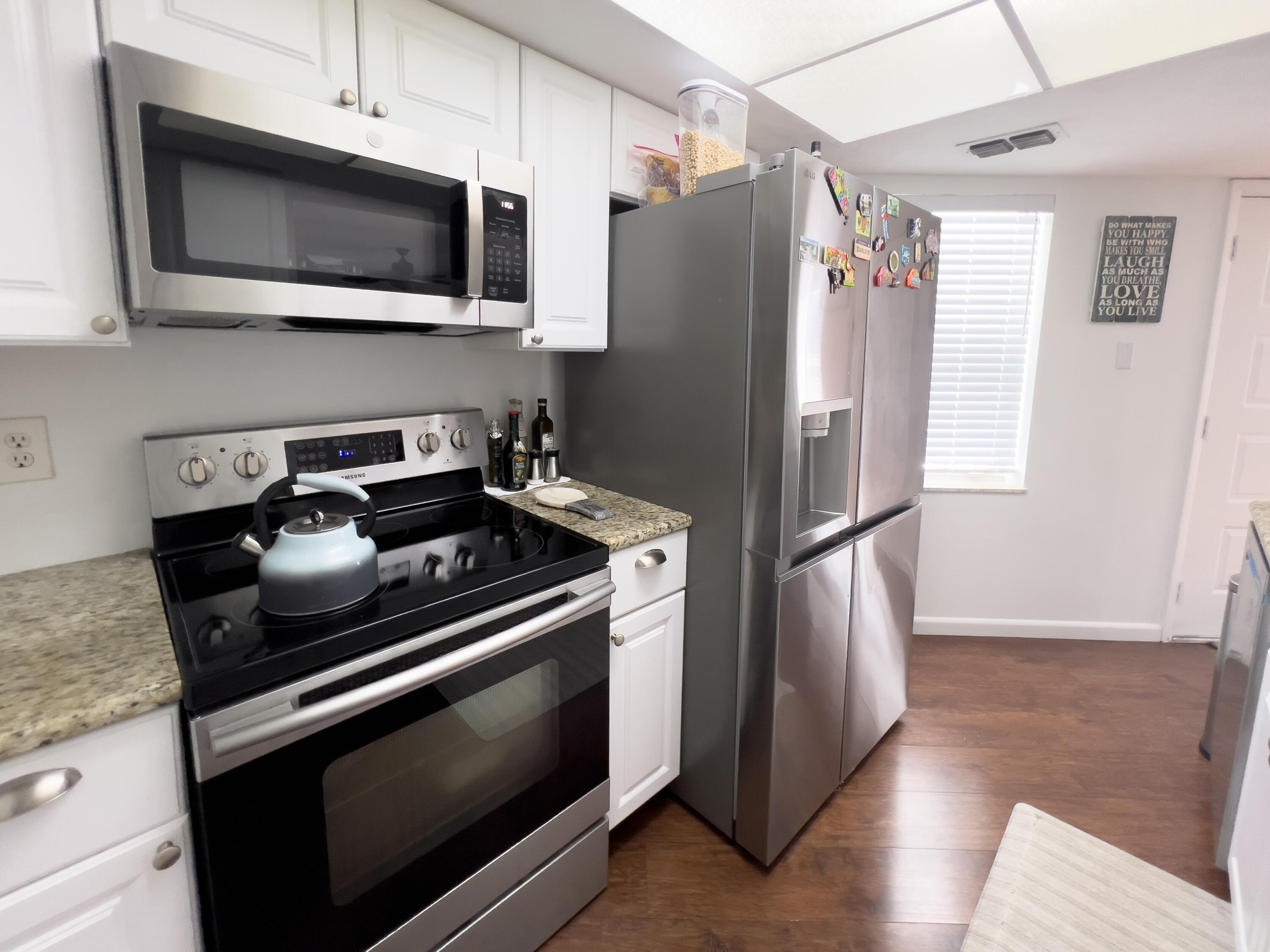 3278 Southeast Aster Lane, Unit 255 Stuart, FL 34994 - Photo 8 of 12 a kitchen with stainless steel appliances granite countertop a refrigerator microwave and sink
