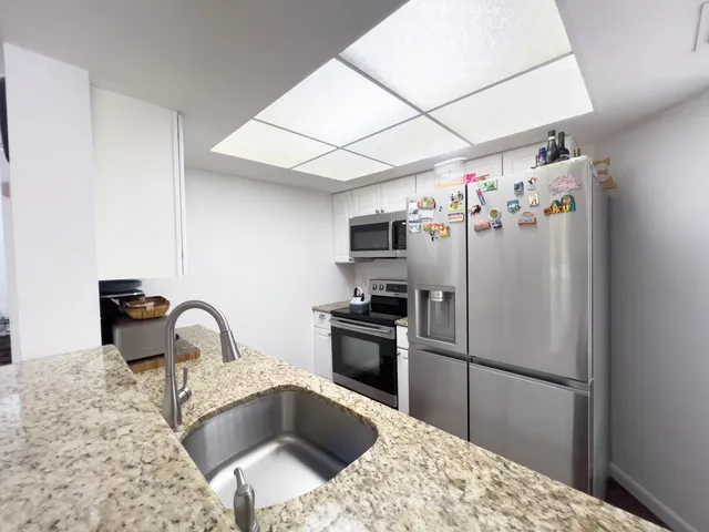 a kitchen with stainless steel appliances granite countertop a refrigerator a sink a stove and a refrigerator