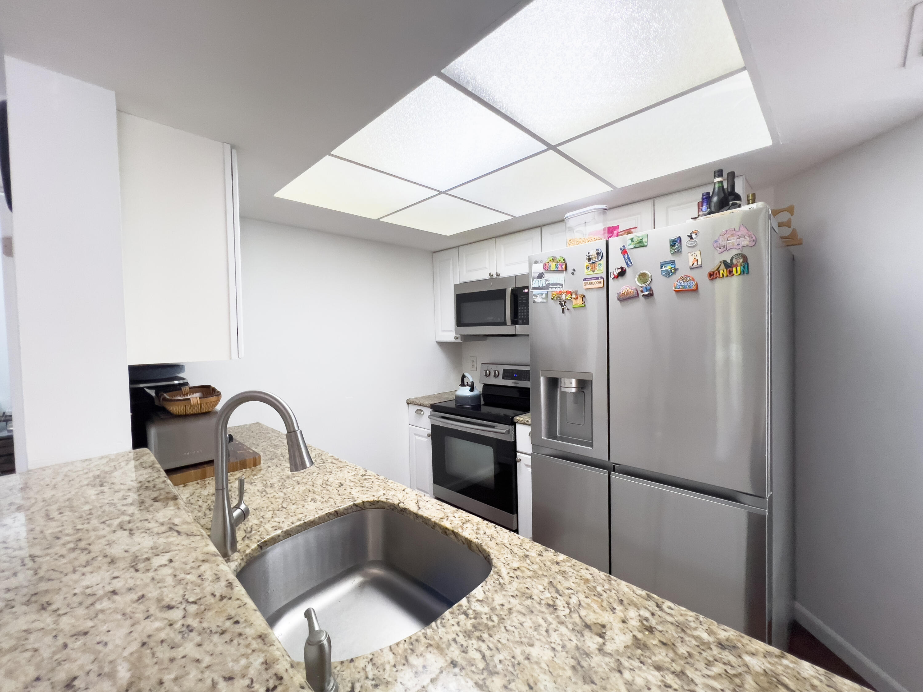 3278 Southeast Aster Lane, Unit 255 Stuart, FL 34994 - Photo 9 of 12 a kitchen with stainless steel appliances granite countertop a refrigerator a sink a stove and a refrigerator