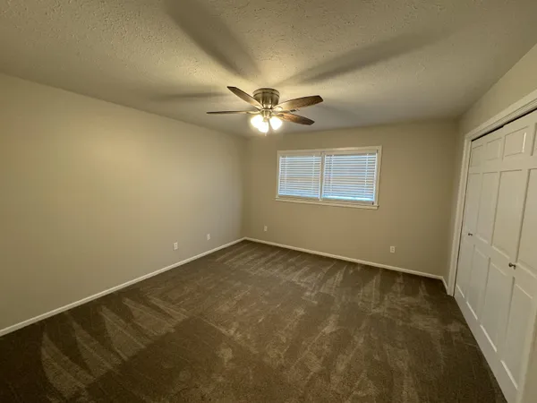 an empty room with windows and fan