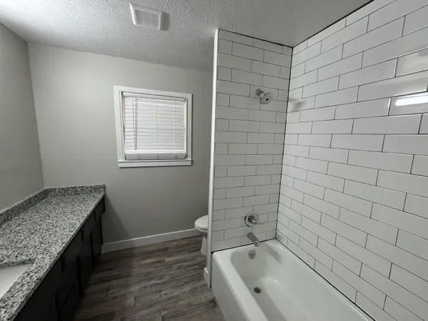 a bathroom with a granite countertop sink toilet and bathtub