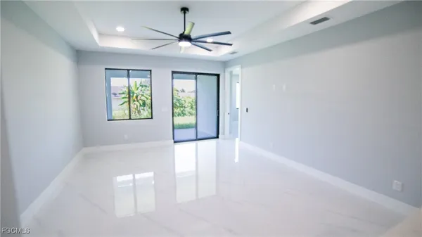 an empty room with windows and ceiling fan
