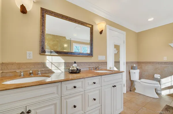 a bathroom with a toilet a double vanity sink and a mirror