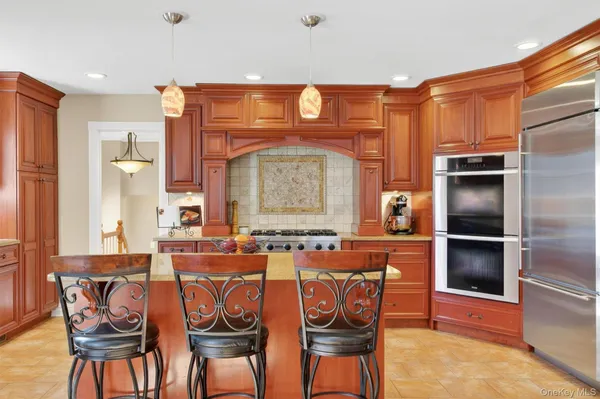 a dining hall with stainless steel appliances a stove a sink dishwasher a dining table and chairs with wooden floor