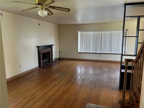an empty room with wooden floor fan and windows