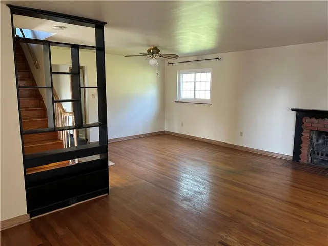 an empty room with wooden floor closet and windows