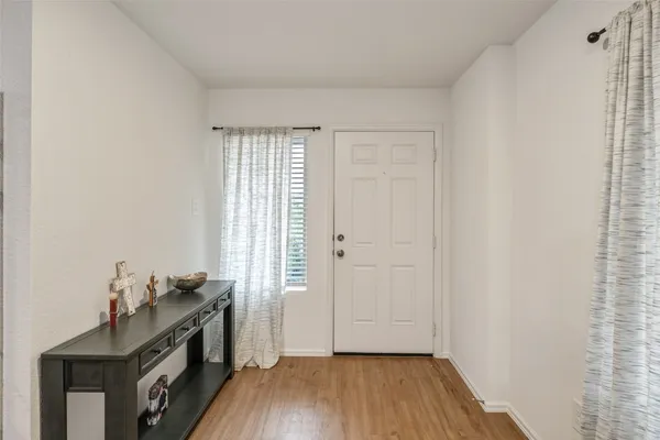 a view of an empty room with a window and wooden floor