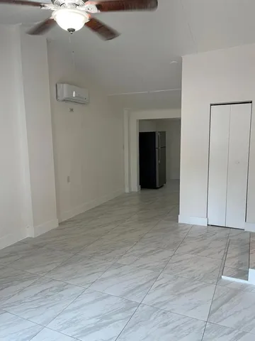 a view of an empty room with chandelier fan