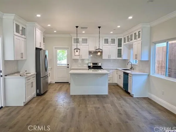 a large kitchen with stainless steel appliances kitchen island granite countertop a stove a refrigerator a sink and a oven