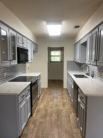 a kitchen with stainless steel appliances granite countertop a sink stove and cabinets