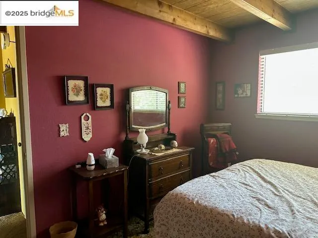 a bedroom with a bed and a dresser next to a window