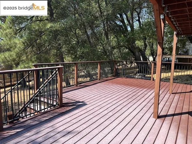 a balcony with wooden floor and large trees