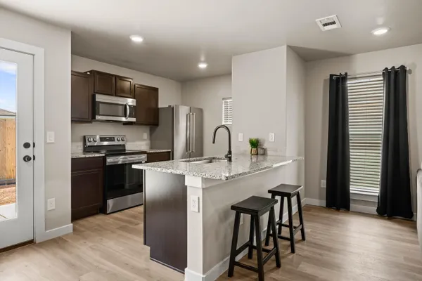 a kitchen with stainless steel appliances granite countertop a stove a sink a microwave a dining table and chairs