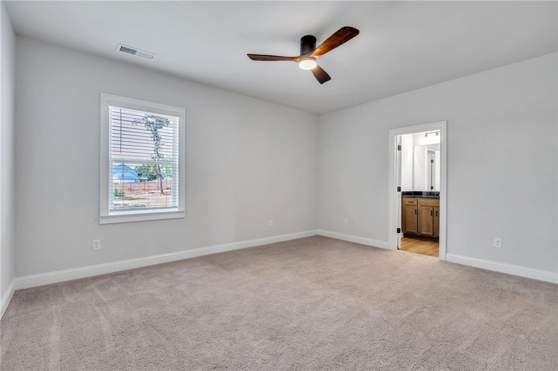 226 Holly Br Road Piedmont, SC 29673 - Photo 34 of 44 A spacious bedroom with a warm carpet, featuring an overhead ceiling fan and a connecting bathroom.