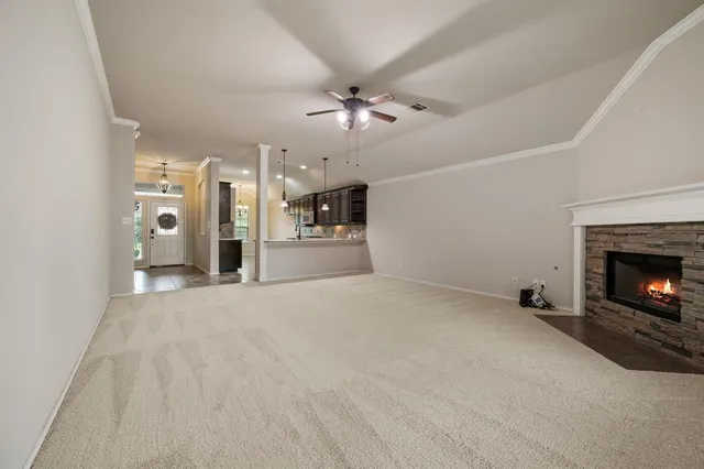 a view of a livingroom with a fireplace a chandelier fan and windows
