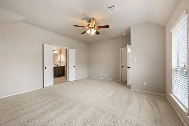an empty room with chandelier fan and windows