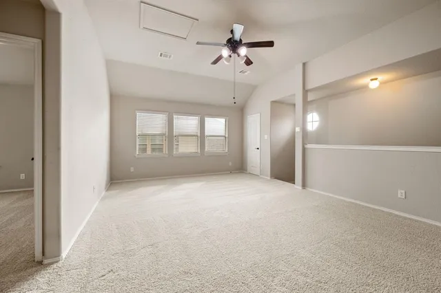 an empty room with chandelier fan and windows